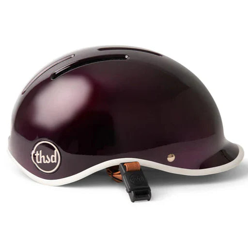 Dark cherry coloured helmet with leather look strap and a Thousand logo on a white background